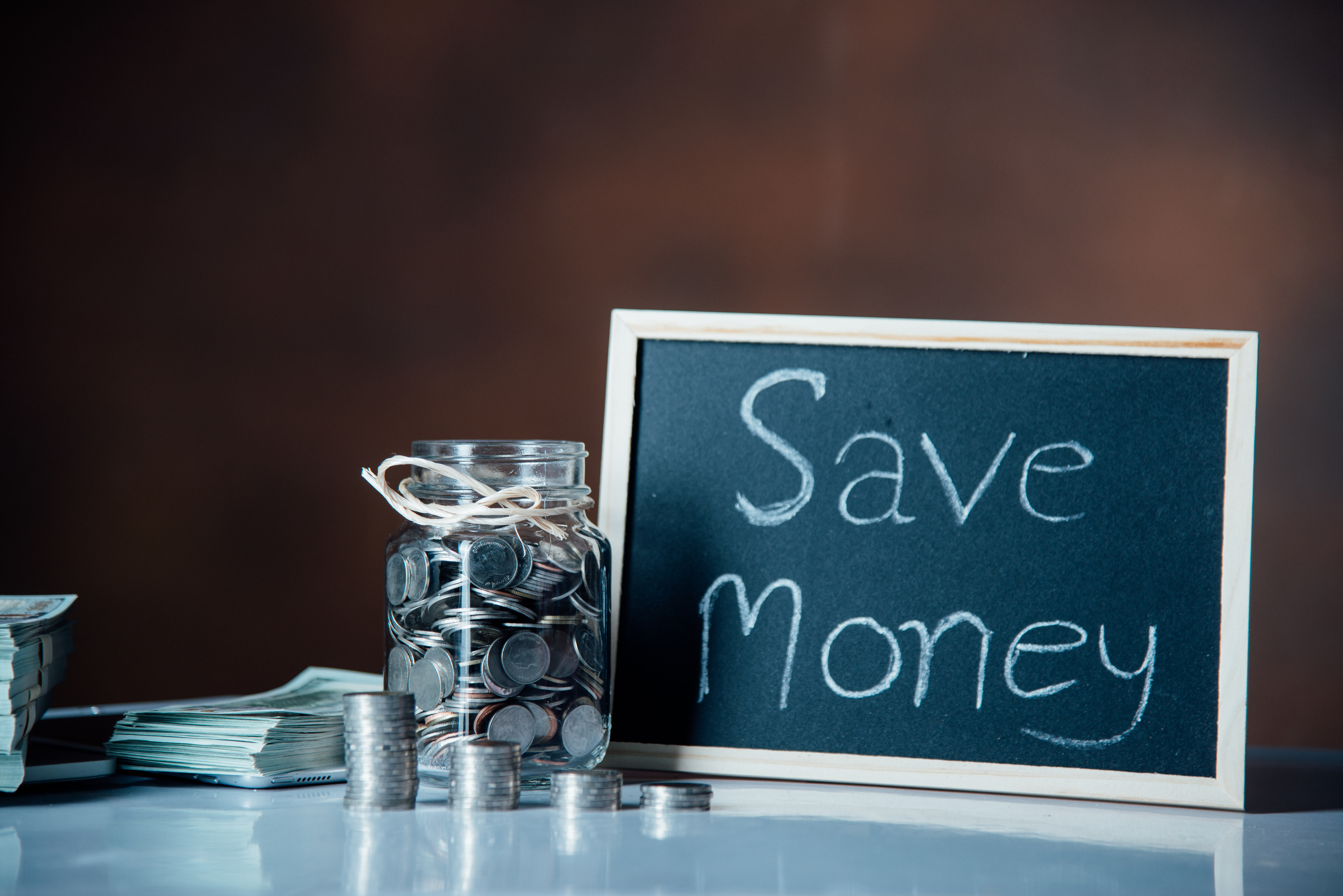 Save money sign next to coins and a jar
